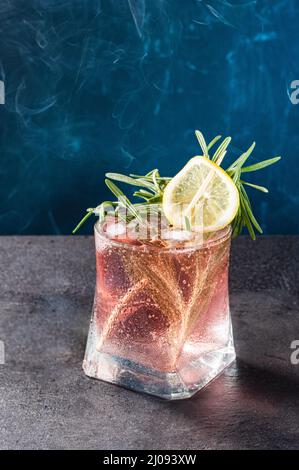 Erfrischender, kalter Cocktail. Cocktail mit Zitrone und Limonade. Rosafarbener Cocktail auf blauem Hintergrund. Stockfoto