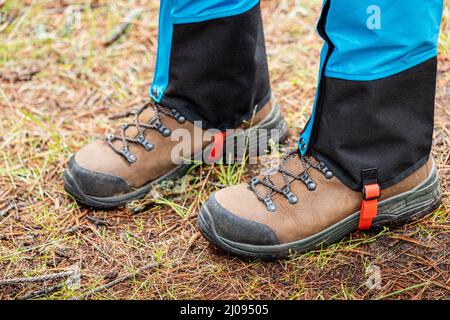 Wanderer trägt Gamaschen über Trekkingstiefeln, um sich vor Wasser, Insekten und Kälte zu schützen. Kleidung und Ausrüstung für Rucksackreisen und Camping Stockfoto