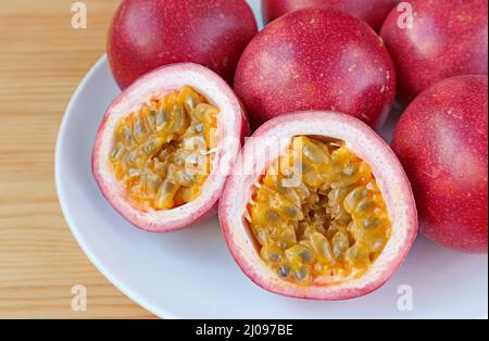 Köstliche, halbreife Passionsfrucht mit einer Vielzahl von Vollfrüchten im Hintergrund Stockfoto