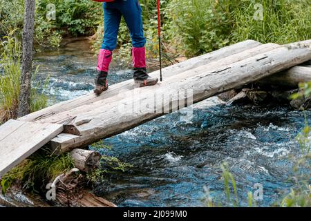 Wanderer trägt Gamaschen über Trekkingstiefeln, um sich vor Wasser, Insekten und Kälte zu schützen. Kleidung und Ausrüstung für Rucksackreisen und Camping Stockfoto