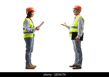 Reifer männlicher Ingenieur, der mit einer jungen Ingenieurin auf blauem Hintergrund isoliert spricht Stockfoto