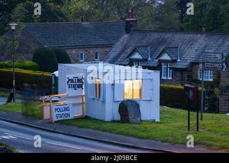 Wahllokal am Wahltag in der ländlichen Gemeinde (vorübergehende Metallhütte, offene Tür, verschwommene Wähler) - Burley Woodhead, West Yorkshire, England, Großbritannien. Stockfoto