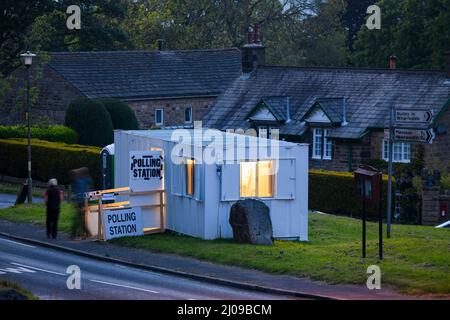 Wahllokal am Wahltag in der ländlichen Gemeinde (vorübergehende Metallhütte, offene Tür, verschwommene Wähler) - Burley Woodhead, West Yorkshire, England, Großbritannien. Stockfoto