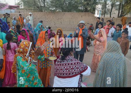 Bahawalpur, Punjab, Pakistan. 15. März 2022. Mitglieder von Rwadari Tehreek Pakistan und Hindu-Gemeinschaft feiern ihr religiöses Fest von Holi, bekannt als Fest der Farben in einem Dorf im Distrikt Bahawalpur. Holi markiert den Beginn des Frühlings und den Triumph des Guten über das Böse. Zu den Feierlichkeiten gehört das Werfen von farbenfroher Farbe, Pulver und Wasser auf die Menschen. Holi beobachtete in Pakistan am Ende der Wintersaison auf dem letzten Vollmond des Mondmonats. (Bild: © Rana Sajid Hussain/Pacific Press via ZUMA Press Wire) Stockfoto