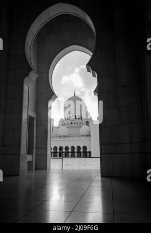 Ein Blick auf eine Kuppel der Scheich-Zayed-Moschee durch einen Bogen. Wunderschöne und prächtige Moschee aus Abu dhabi. Schwarzweiß-Foto Stockfoto