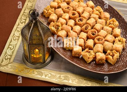 Festessen im Ramadan. Baklava serviert in einem großen Teller, zusammen mit einer traditionellen ägyptischen Laterne platziert. Stockfoto