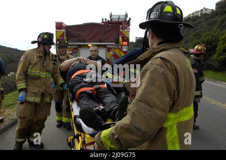 San Diego Feuerwehr-Rettungskräfte von den Stationen 20 und 36, die eine technische Rettung eines Fahrers bei einem überfahrenden Unfall im Gelände durchführen. Stockfoto