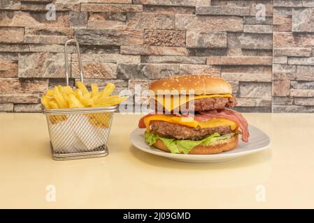 Der doppelte Hamburger mit zwei Fleischstücken gewürzt mit einer Prise Salz und Pfeffer Ketchup und Cheddar-Käse auf dem Sahnetafel und Portion Pommes frites i Stockfoto