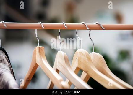 Kleiderbügel aus Holz zum Aufhängen von Kleidung an einem hellbraunen Kleiderständer Stockfoto