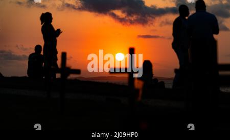 Silhouette von Menschen und Kreuzen, die auf dem Boden zu Ehren der von Covid-19 Getöteten befestigt sind. Sonnenuntergang in Salva Stockfoto