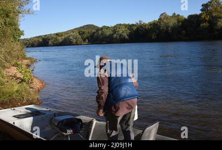 Älterer Mann bereitet sich auf den White River im Norden von Arkansas vor. Er startet von Boswell Shoals aus. Er trägt eine blaue Daunenweste und ha Stockfoto