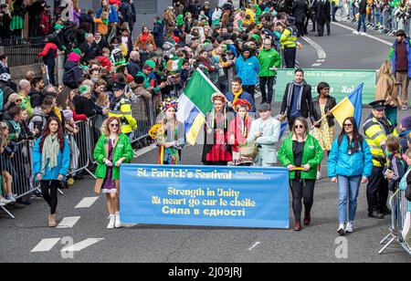 Dublin, Irland. 17. März 2022. Die Teilnehmer halten ein Spruchband mit der Aufschrift: Irisch und Ukrainisch führen von der St. Patrick's Day Parade in Dublin ab drei Jahre seit Irland zum letzten Mal den St. Patrick's Day vollständig feiern konnte, markierten Dubliners und Besucher den Tag mit der Ukraine und ihren Menschen in ihren Köpfen und in ihren Herzen. Die vorherrschende Farbe der festlichen Parade durch die Straßen der Hauptstadt war nicht nur grün, sondern auch blau und gelb. Kredit: SOPA Images Limited/Alamy Live Nachrichten Stockfoto