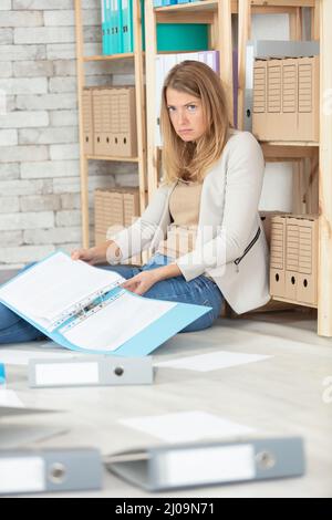 Geschäftsfrau in einem Schrank mit Laptop und Stapel von Dateien Stockfoto