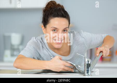 Angehende Klempnerin, die am Wasserhahn arbeitet Stockfoto