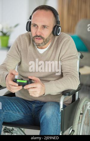 Spieler im Rollstuhl spielt Videospiele mit Kopfhörern Stockfoto