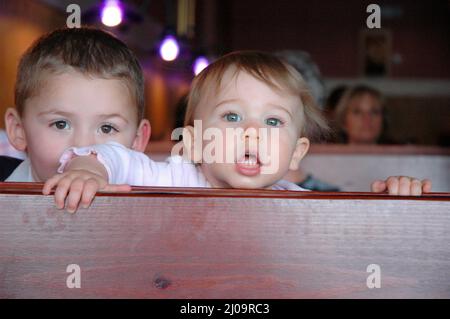 Sehr junge Kinder und Kleinkinder im Café, die sich beim Mittagessen mit der Großfamilie vor Brüdern und Schwestern und der Familie zeigen Stockfoto