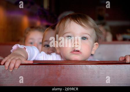 Sehr junge Kinder und Kleinkinder im Café, die sich beim Mittagessen mit der Großfamilie vor Brüdern und Schwestern und der Familie zeigen Stockfoto