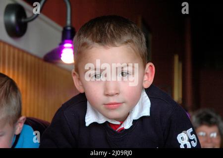 Sehr junge Kinder und Kleinkinder im Café, die sich beim Mittagessen mit der Großfamilie vor Brüdern und Schwestern und der Familie zeigen Stockfoto