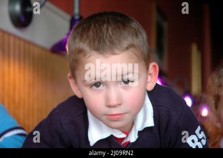 Sehr junge Kinder und Kleinkinder im Café, die sich beim Mittagessen mit der Großfamilie vor Brüdern und Schwestern und der Familie zeigen Stockfoto