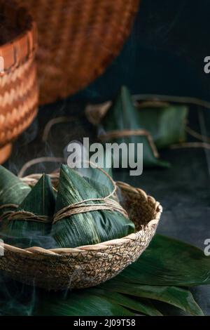 Zongzi Reisknödel шт ein Dampfer für das traditionelle chinesische Drachenbootfest (Duanwu Festival) auf dunkelschwarzem Hintergrund Stockfoto