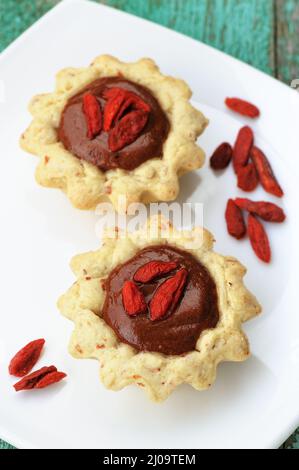 Zwei leckere hausgemachte Fancy Kuchen mit Schokoladencreme und trockenen Goji-Beeren in weißen Teller vertikal Stockfoto