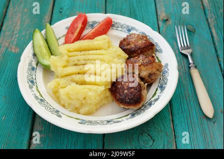 Kartoffelpüree und drei hausgemachte Fleischkoteletts mit frischen Gurken und Tomaten horizontal Stockfoto