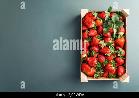 Reife rote Erdbeere in einer Holzkiste. Erdbeerhintergrund. Ansicht von oben auf die Erdbeere; Stockfoto