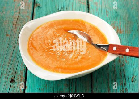 Hausgemachtes Kürbissuppenpüree mit Sesam auf türkisfarbenem Tisch aus der Nähe Stockfoto