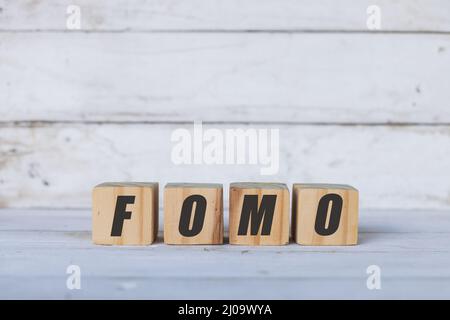 FOMO-Konzept auf Holzwürfeln oder Blöcken geschrieben, auf weißem Holzhintergrund. Stockfoto
