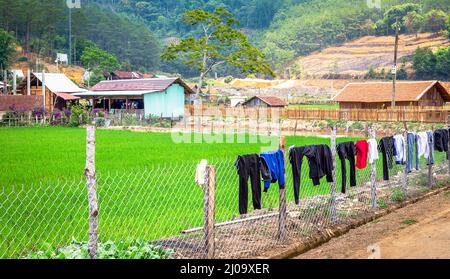 Wäsche hängt an einem Zaun in einem Dorf im Hochland von Zentralvietnam. Stockfoto