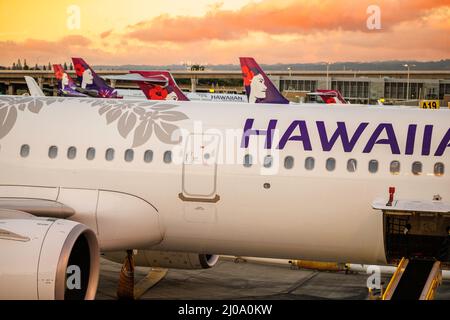 Ein Blick auf den Sonnenuntergang über den Jets von Hawaiian Airlines im Interisland Terminal am Honolulu International Airport, Oahu, Hawaii, USA. Stockfoto