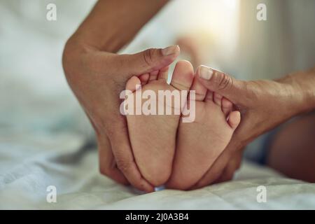 Es gibt nichts ganz so süßes wie kleine Babyfüße. Aufnahme einer unverkennbaren Mutter und ihren Kinderfüßen zu Hause. Stockfoto