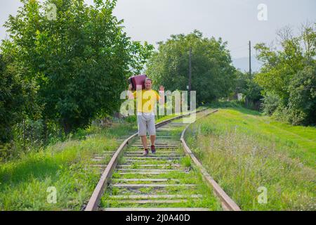 Ein Mann, der einen roten Koffer auf seiner Schulter trägt Stockfoto