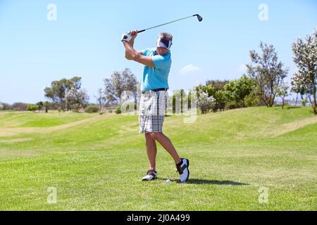 Eine gute Fahrt bewundernd. Ein reifer Mann, der einen Golfschuss auf dem Golfplatz spielt. Stockfoto