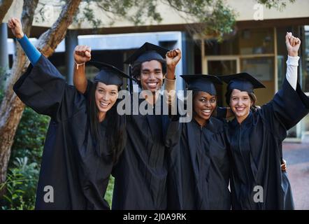 Nichts kann uns jetzt aufhalten. Eine Gruppe lächelnder Hochschulabsolventen feiert ihren Abschluss. Stockfoto