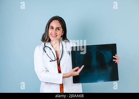 Die hispanische Ärztin betrachtet Röntgenaufnahmen in der Radiologieklinik auf blauem Hintergrund in Mexiko-Lateinamerika Stockfoto