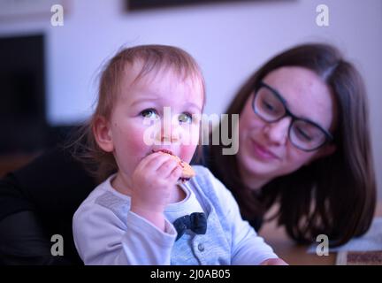 Mutter hält ihren niedlichen kleinen Jungen, der Cookie isst Stockfoto