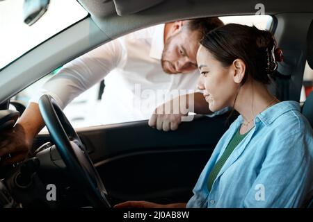 Mit dieser Taste wird das Fahrzeug gestartet. Aufnahme eines Geschäftsmannes, der einem Kunden eine Führung durch sein neues Auto gibt. Stockfoto