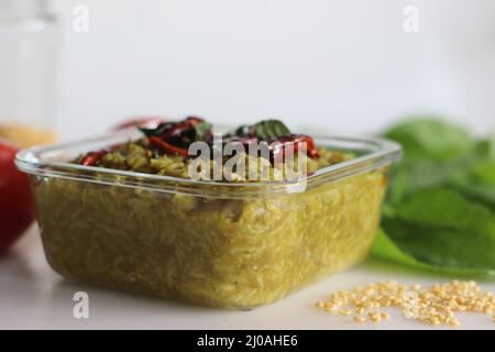 Ein Topf Zubereitung aus Basmati-Reis, gelben Mungellentilen, blanchierten und pürierten Spinat und Gewürzen. Allgemein bekannt als Palak khichdi. Auf Weiß geschossen Stockfoto