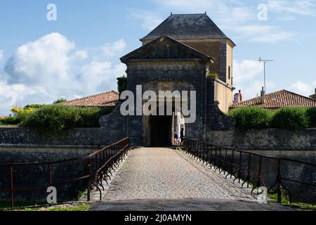 porte des campani in Saint-Martin-de-Ré auf der Ile de Ré an einem sonnigen Tag im Sommer mit Menschen, die auf einem Fahrrad darunter reiten. Stockfoto