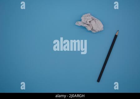 Bleistift und zerknittertes Stück Papier isoliert auf blauem Hintergrund mit Kopierplatz Stockfoto
