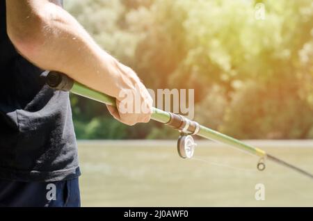 Fischer mit einer Angelrute in der Hand. Ein Mann steht am Ufer des Flusses mit einer Angelrute. Angeln und Erholung auf dem Land Konzept Stockfoto