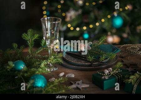 Weihnachtliche Tischeinstellung mit leerem schwarzen Keramikplatte, Tannenzweigen und grünen Geschenkboxen auf dunklem Holzhintergrund Stockfoto