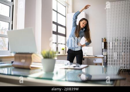 Frau In Hijab Steht Und Dehnt Sich Vor Dem Computer Stockfoto