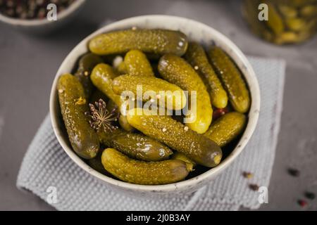 Teller mit Gurken, eingelegte Gurken auf grauem Betongrund. Sauberes Essen, vegetarisches Konzept Stockfoto