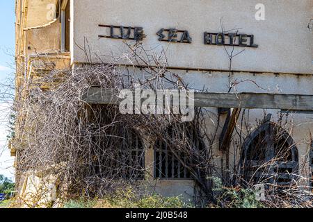 Der Bezirk Varosha (Kapalı Maraş) in Famagusta (Zypern) war zwischen 1970 und 1974 eines der beliebtesten Reiseziele der Welt. Die griechisch-zyprischen Einwohner flohen 1974 während der türkischen Invasion auf Zypern, als die Stadt Famagusta unter türkische Kontrolle kam. Seither ist sie verlassen und die Gebäude sind verfallen. Die meisten der ursprünglichen Bewohner von Varosha (und ihre direkten Nachkommen) leben heute südlich der UN-Pufferzone Zyperns. Diese Familien sind immer noch die legalen Eigentümer von Eigentum in Varosha, aber während die Stadt umkämpft wird, können sie es nicht zurückfordern. Und viele Stockfoto