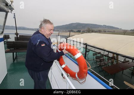 Saalburg Ebersdorf, Deutschland. 17. März 2022. Kapitän Klaus-Peter Pretzsch legt die Rettungsschwimmer in den Halter an Bord des Schiffes 'Thüringer Meer'. Die drei Schiffe der Reederei Stausee liegen an den Ufern des Bleiloch-Staudamms. Hier sind sie auf die Saison vorbereitet. (To dpa: Sieben Zeichen des Frühlingserwachens in Thüringen) Quelle: Bodo Schackow/dpa-zentralbild/dpa/Alamy Live News Stockfoto