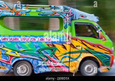 Philippinischen Mann fahren eine sehr bunte Jeepney-Mini-van Stockfoto