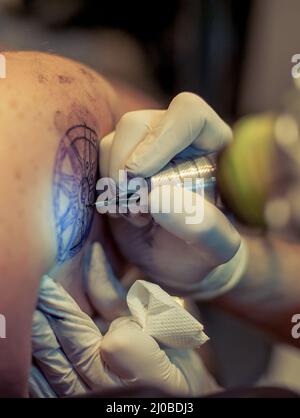 Master Tattoo zeichnet die blaue Farbe auf dem Kunden Tattoo Stockfoto