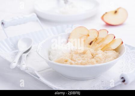 Apfelmus-Dessert mit Rahm und frischen Äpfeln in einer weißen Schüssel auf einem weißen Tee-Tablett Stockfoto